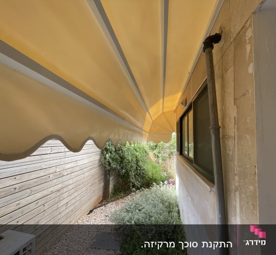 סוכך צהוב מותקן מעל שביל חצר